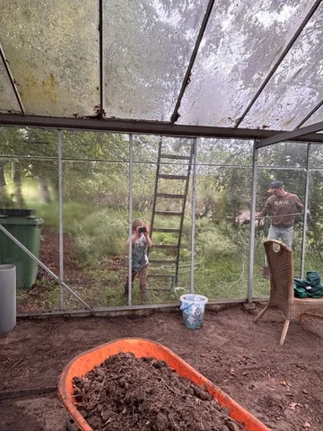 Kruiwagen met aarde in de lege kas tijdens de verbouwing