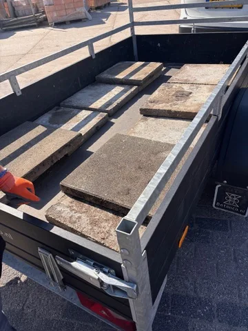 Zware betontegels op een aanhanger voor de nieuwe vloer van de kas