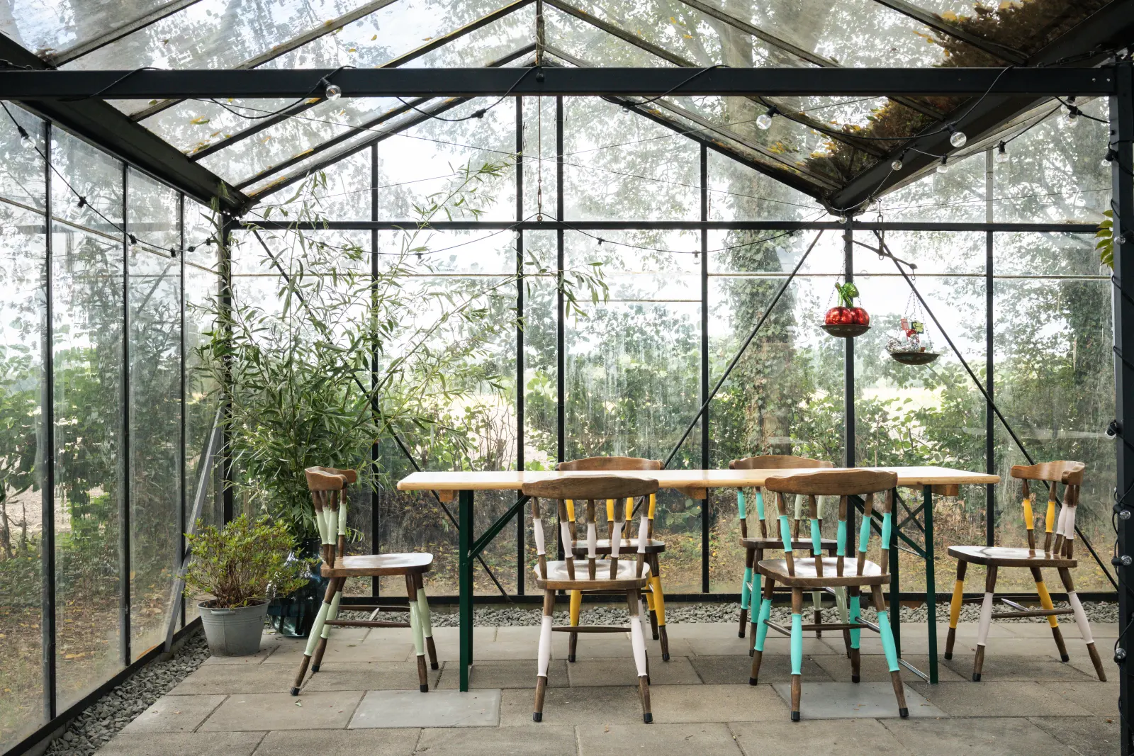 Lichte kas met lange houten tafels en stoelen voor een fotoshoot in Breda