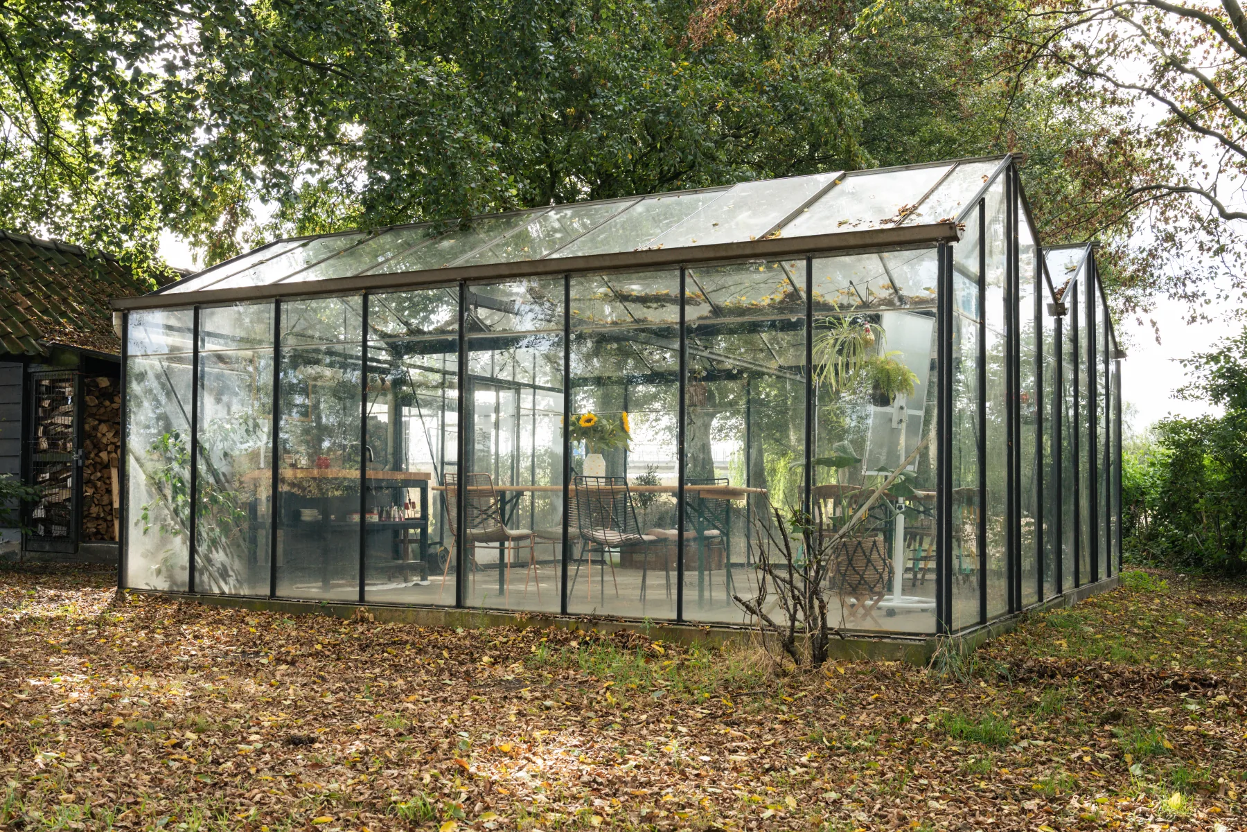 De glazen kas van Boerderij Ons Buiten tussen de bomen in Breda