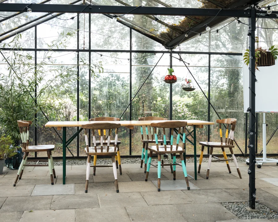 Vergaderopstelling met lange houten tafel en stoelen in onze kas in Breda