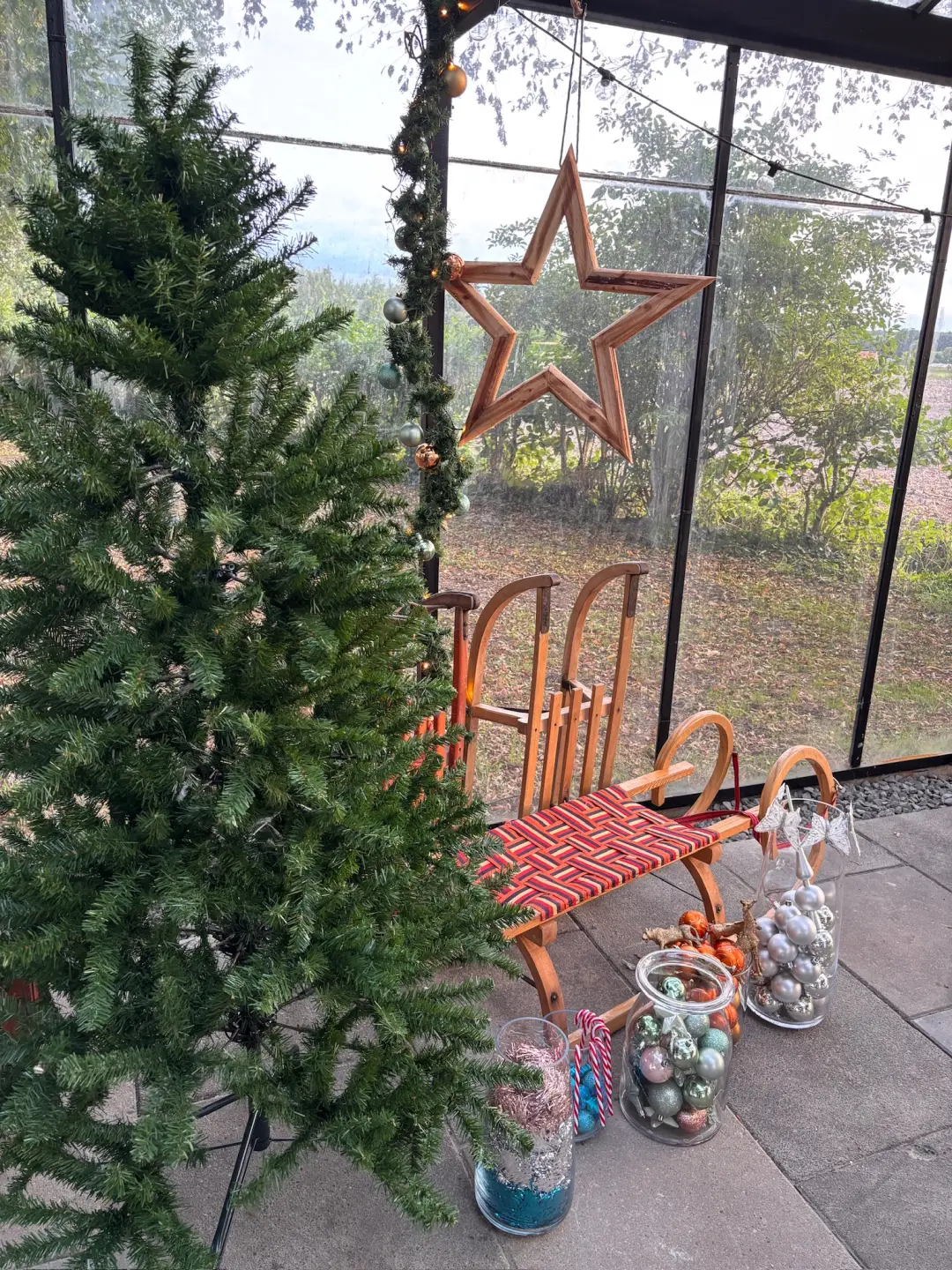 Kerstdecoratie met een houten slee in de kas van Boerderij Ons Buiten
