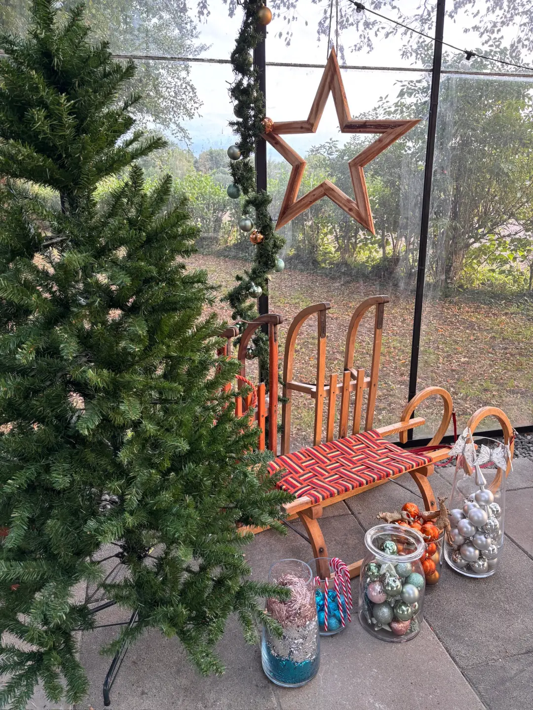 Kerstboom, houten slee, sterren en decoraties in de kas